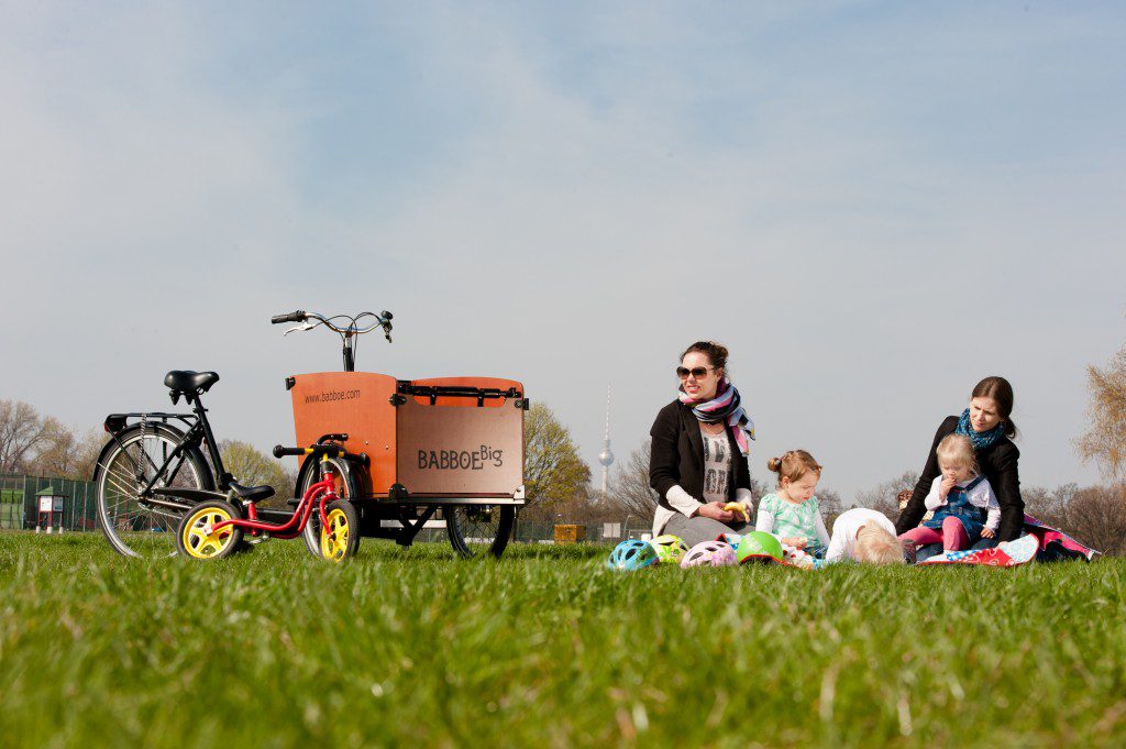 Bici de carga en parque con familia haciendo picnic